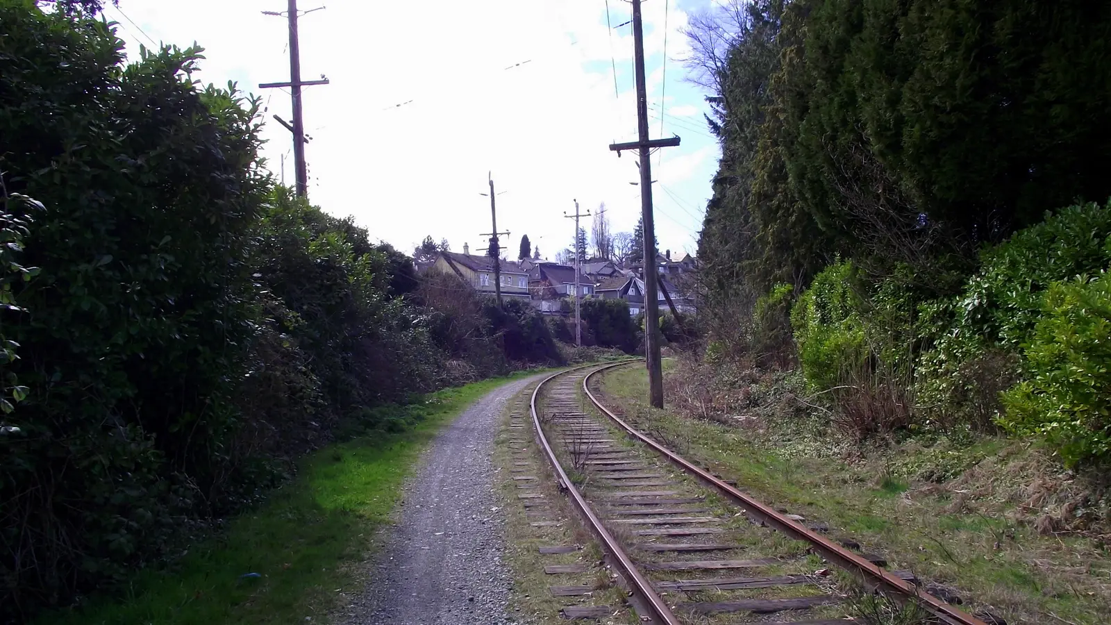The historic Arbutus railway corridor and greenway path curving past residential homes in Arbutus